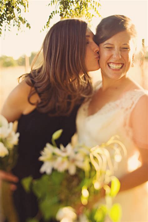 Beautiful Bride Laughing As Bridesmaid Kisses Her On The Cheek Photo