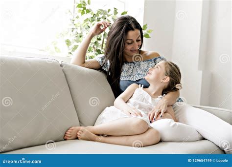 Portrait Of Beautiful Mother And Her Little Daughter Sitting Together On Couch Stock Image