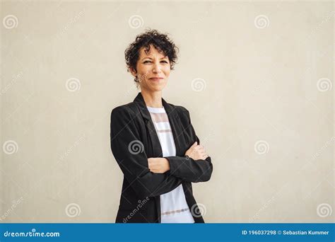Portrait Of Smiling Mature Business Woman Standing Arms Crossed Against