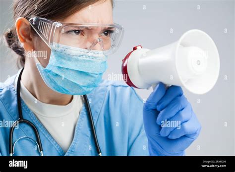 Woman Doctor Shouting Over Megaphone Wearing Face Mask And Protective Eye Wear Goggles Stock