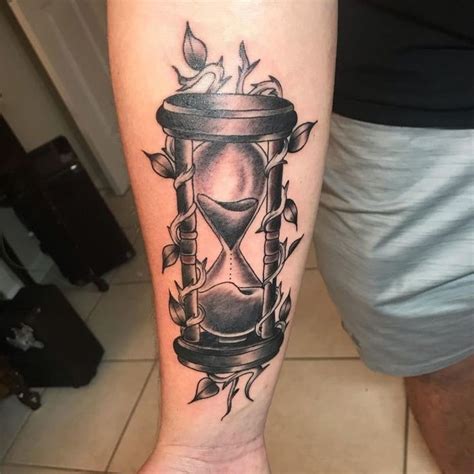 A Tattoo On The Arm Of A Man With An Hourglass
