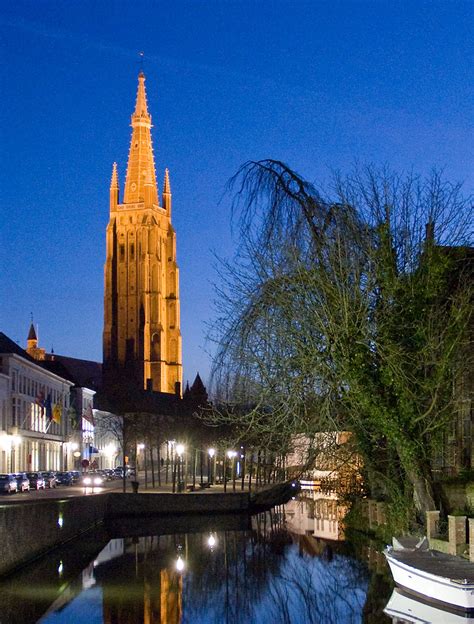 A short bridge surrounded by tall trees, old flemish houses lining the canal and the sound of water gushing through. File:Church of Our Lady - Bruges, Belgium - panoramio.jpg ...