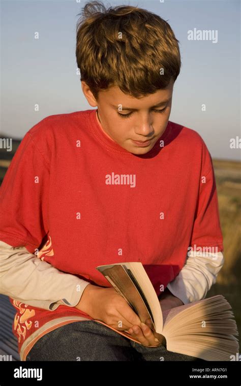 Young Boy Reading Book Outdoors Stock Photo Alamy
