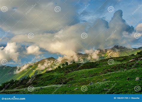 Beautiful Mountain Landscape With Green Slopes And Snow And Clouds