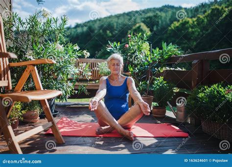A Senior Woman Sitting Outdoors On A Terrace In Summer Doing Yoga