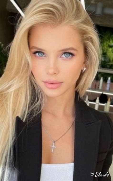 A Beautiful Blond Woman With Blue Eyes Wearing A Black Blazer And Cross