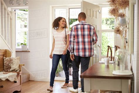 Man Opens Front Door For Woman Returning Home From Work Stock Photo