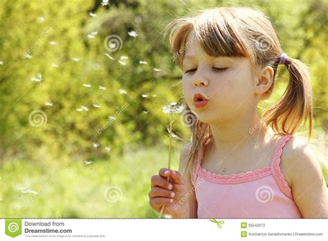 Beautiful Little Girl Blowing On A Dandelion Stock Photo
