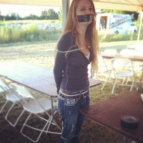 A Woman Standing In Front Of A Picnic Table With Her Mouth Taped To The