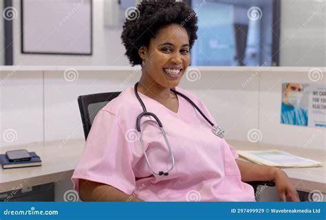 Portrait Of Happy African American Female Doctor Sitting In Hospital