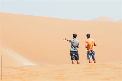 Two Men On A Dune In Desert Landscape One Of Them Pointing Something