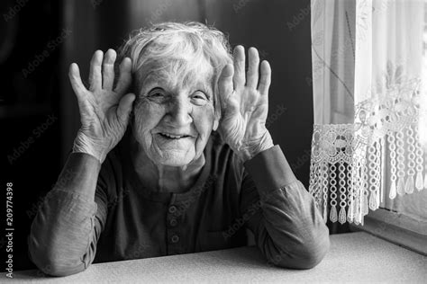 Portrait Of Cheerful Old Woman Holding Wrinkled Hands Near Her Ears