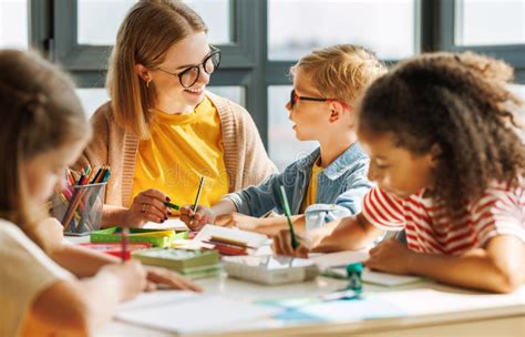 The Friendly Teacher Helping Children With Schoolwork Stock Image