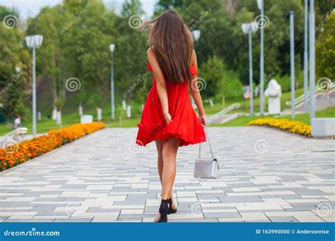Young Beautiful Woman In Red Dress Walking On The Summer Street Stock