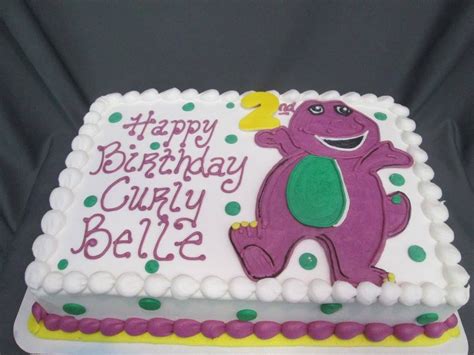 A Birthday Cake With A Purple Dinosaur On Its Side That Says Happy