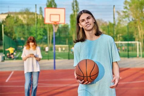 Portrait Of Young Guy Playing Basketball On An Outdoor Game Court Girl