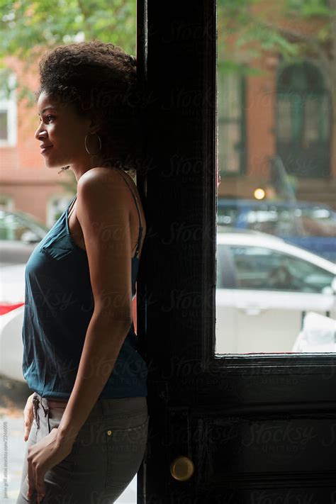 woman leaning on front door of apartment to city street by stocksy contributor jamie grill