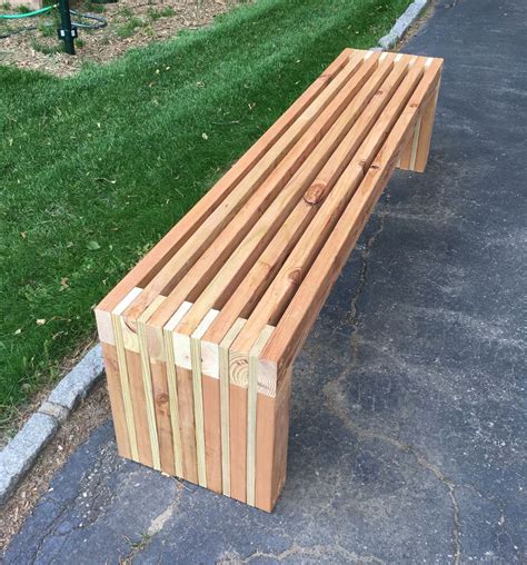 A Wooden Bench Sitting On The Side Of A Road Next To A Grass Covered Park