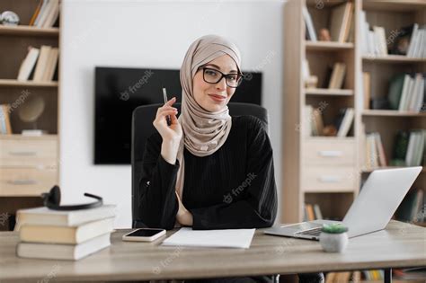Premium Photo Smiling Muslim Woman In Eyeglasses And Hijab Sitting At