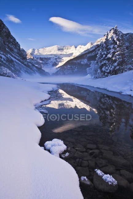 Snow On Shore Of Frozen Lake Louise In Mountains Of Banff National Park