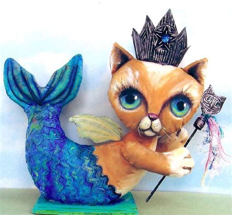 A Figurine Of A Cat With A Crown On Its Head Holding A Wand