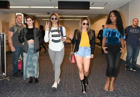 Four Women Are Walking Through An Airport With One Carrying A Handbag