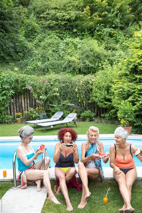 Four Senior Women Happily Eating Watermelon Outdoors By The Pool Del