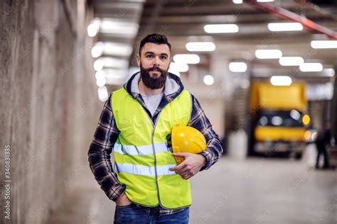 Cute Bearded Construction Worker In Vest And With Safety Helmet In