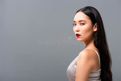 asian woman in satin dress with red lips looking at camera on grey stock image image of