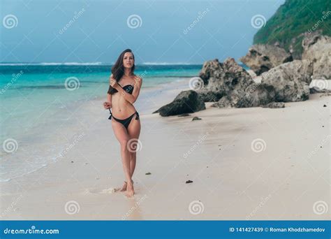 Tanned Model In Black Swimsuit Posing On White Sandy Beach Stock Image