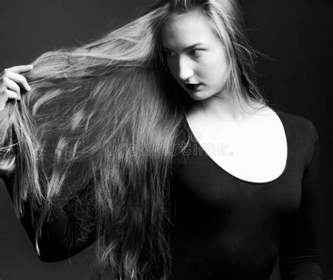 Girl Holding In Hand Shows Off Her Long Blonde Hair On A Dark Background Black And White Stock
