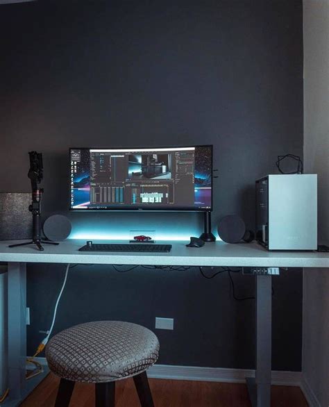 A Desk With A Monitor Keyboard And Speakers On It In Front Of A Gray Wall