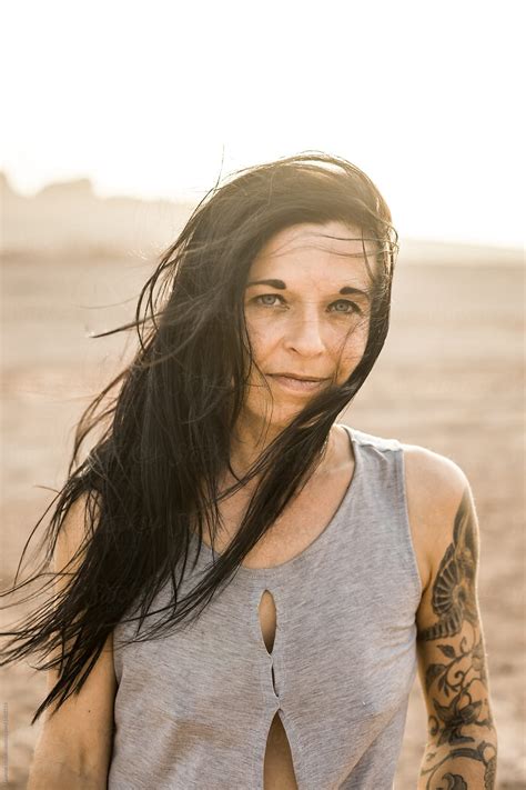 Portrait Of A Black Haired Tattoed Woman With Wind Blown Hair In The Desert By Stocksy