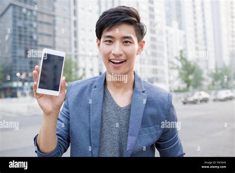 Confident Young Man Showing Smart Phone Stock Photo Alamy