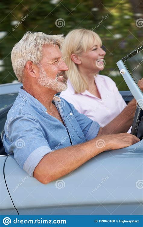 Mature Couple Enjoying Road Trip In Classic Open Top Sports Car