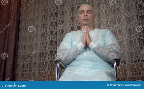 A Bald Young Man With Cancer Looks At The Camera And Prays The Patient