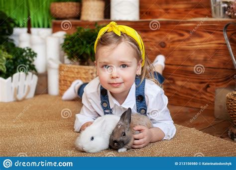 Closeup Portrait Of Cute Little Girl And White And Brown Rabbits Child