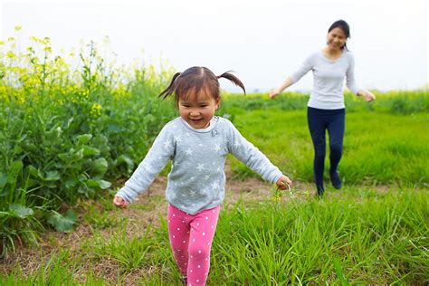 Little Asian Girl Running Outdoor With Her Mother After Del Colaborador De Stocksy Bo Bo