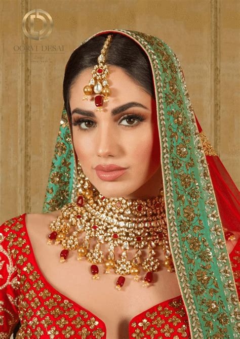 A Woman Wearing A Red And Green Bridal Outfit With Gold Jewelry On Her Neck