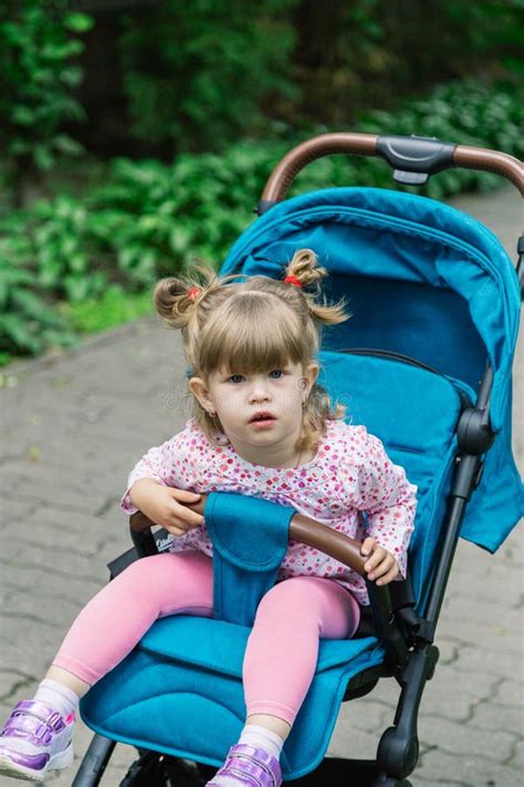 Little Girl Is Sitting In A Pram In A Beautiful Park Stock Image
