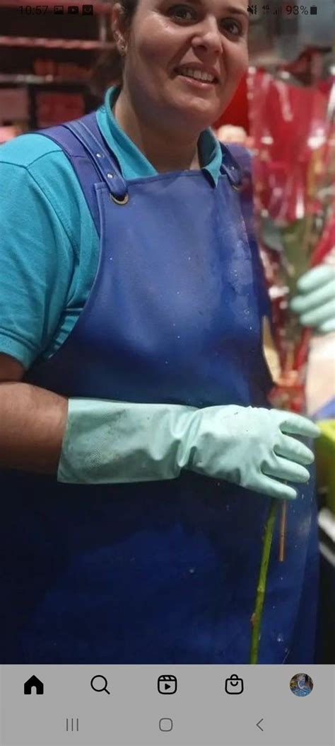 A Woman Wearing Blue Aprons And Green Gloves