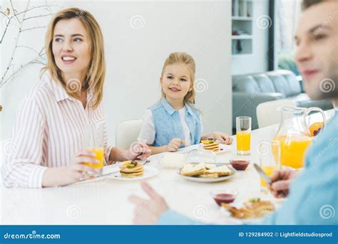 Familia Feliz Que Mira Lejos Mientras Que Desayunando Junto Foto De