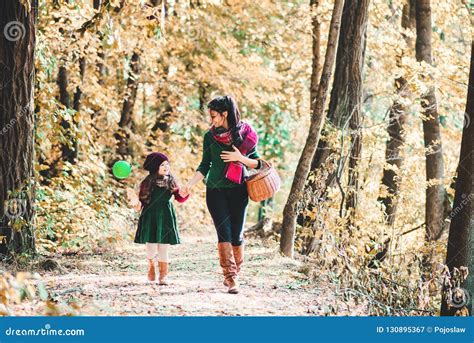A Young Mother With A Toddler Daughter Walking In Forest In Autumn