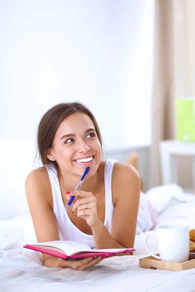 Young Beautiful Woman Lying In Bed Writing A Diary Stock Image