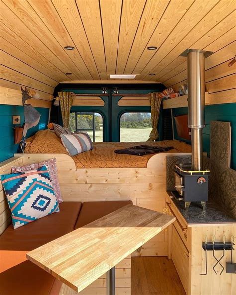 The Interior Of A Camper With Wood Paneling And Blue Walls Including A Bed