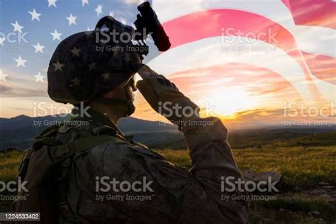 Silhouette Of A Solider Saluting Against Us Flag At Sunrise Stock Photo