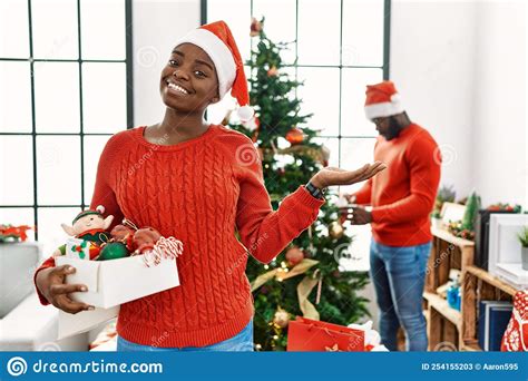 Young African American Couple Standing By Christmas Tree Smiling