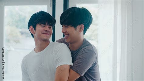 Asian Gay Couple Standing And Hugging Near The Window At Home Young