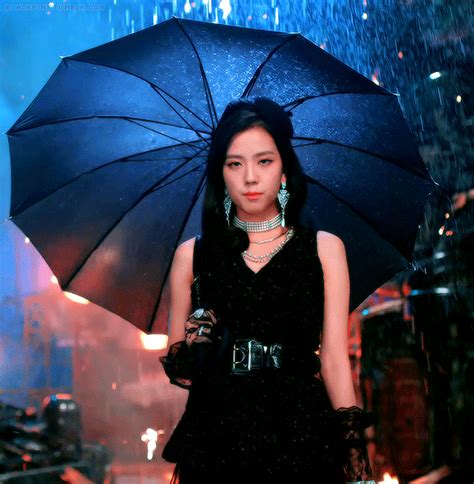 A Woman Holding An Umbrella While Standing In The Rain With Her Hand On