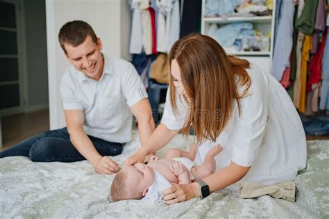 Parents Changing Clothes A Baby Lies In A White Bed Stock Image Image